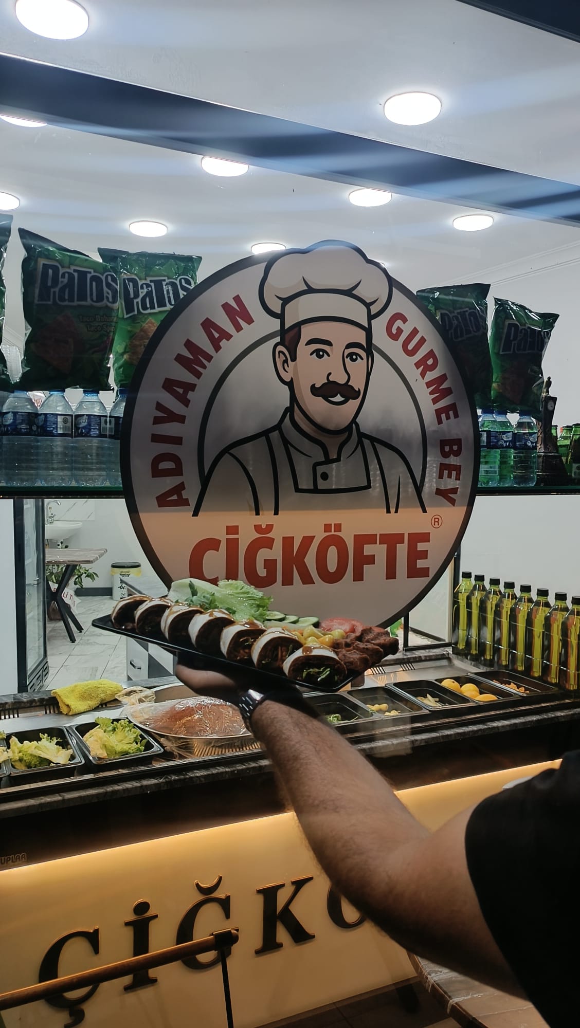 Gurmebey logosu önünde çiğ köfte ve yeşillik sunumu