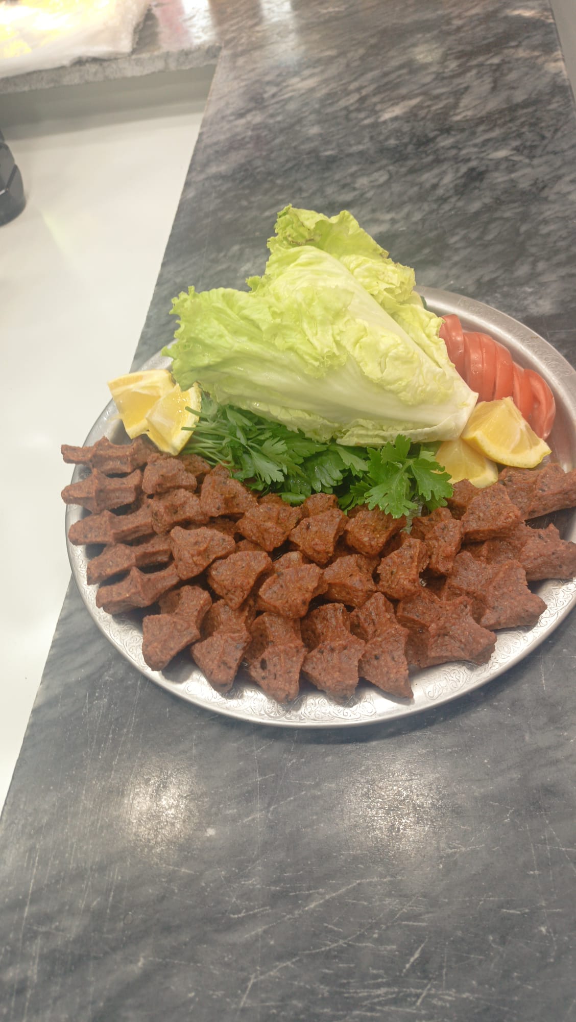 Yeşillik ve limon eşliğinde çiğ köfte tabağı
